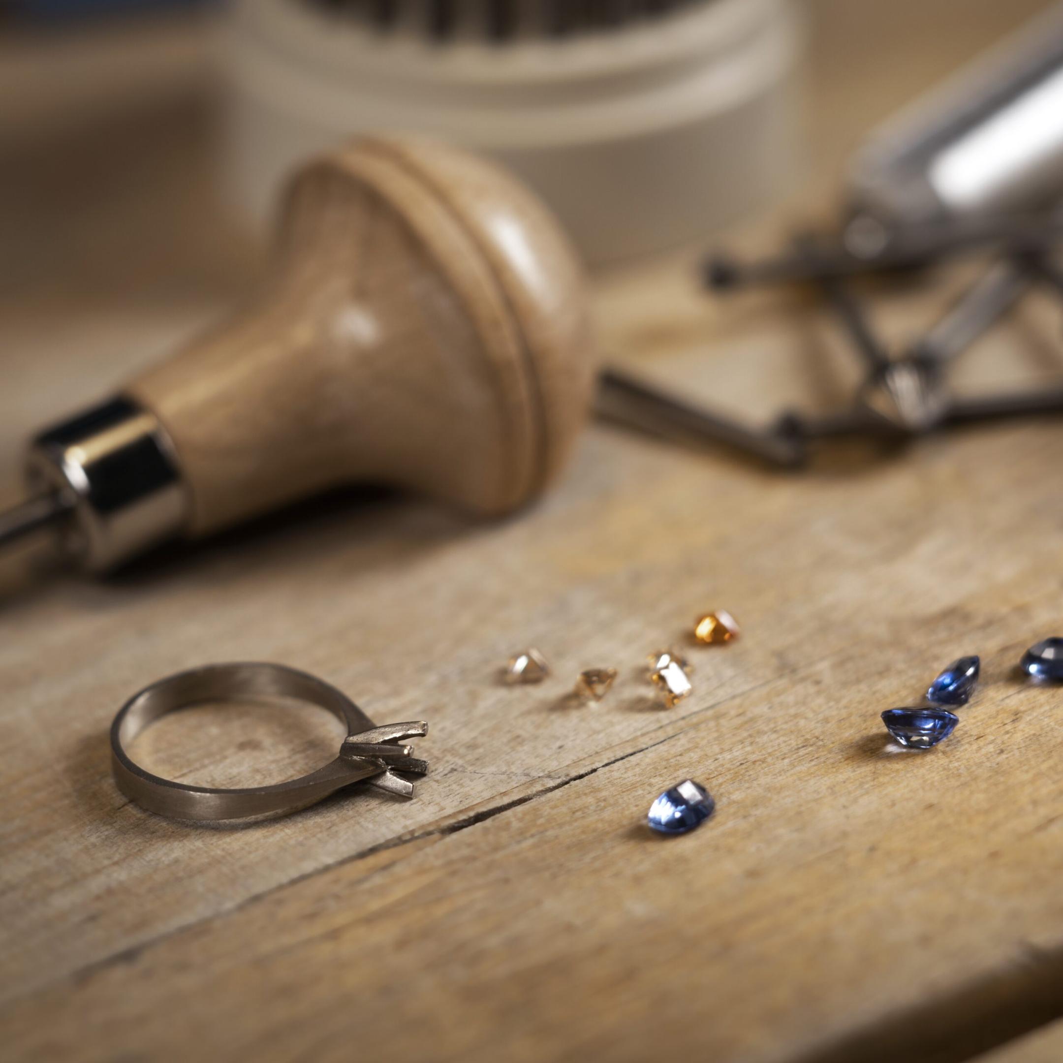 Goldsmith desk while setting synthetic colored cubic zirconia jewellery stones to a ring