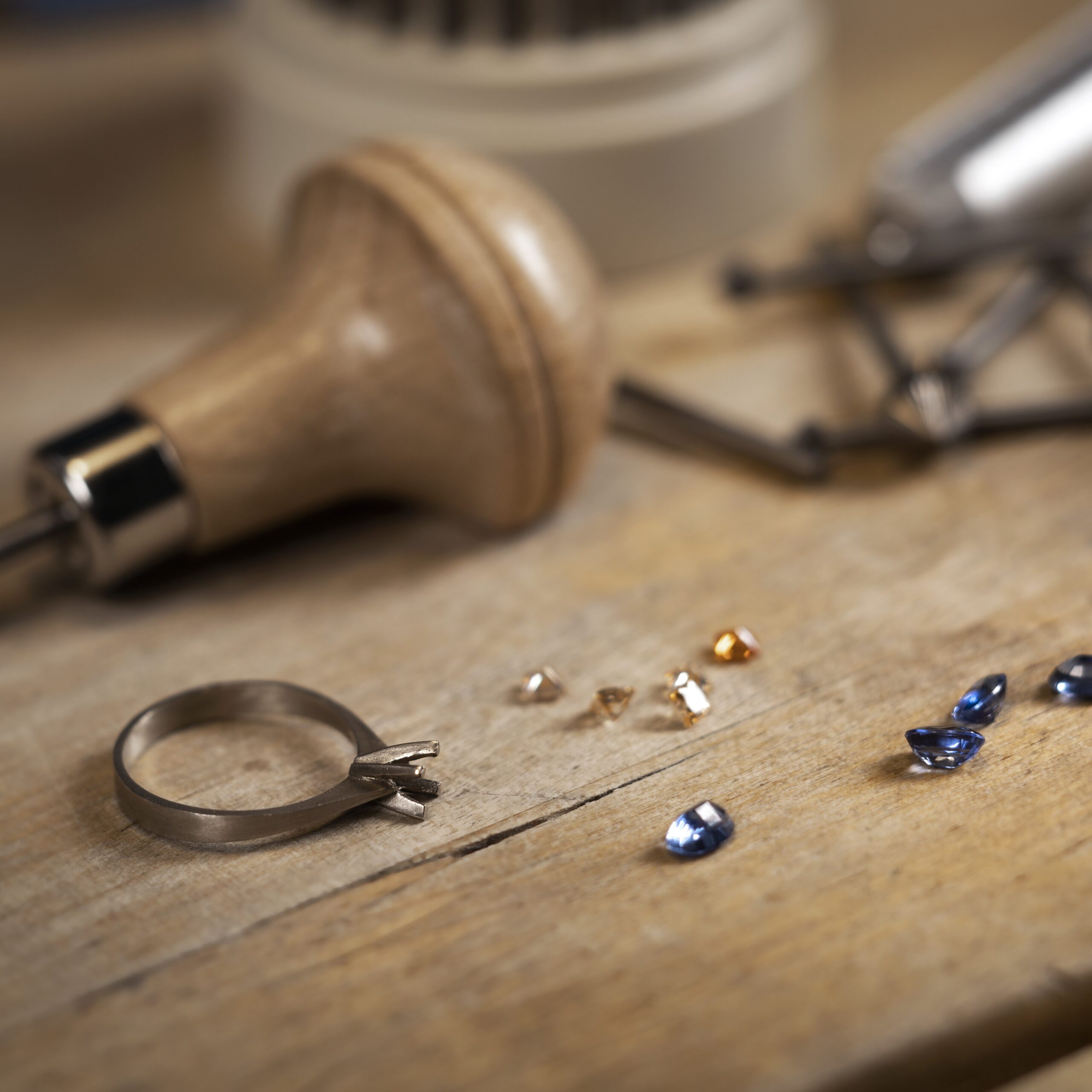 Goldsmith desk while setting synthetic colored cubic zirconia jewellery stones to a ring